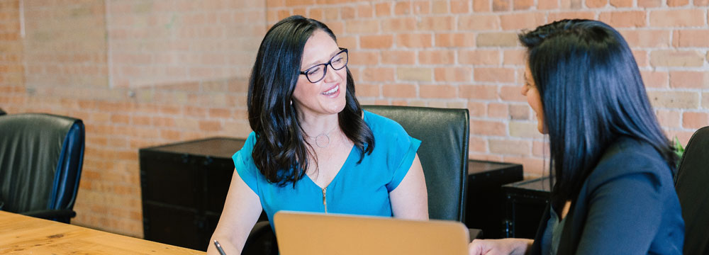 Cliente d'Halifax Consulting discutant devant un bureau avec une consultante de formation commerciale professionnelle